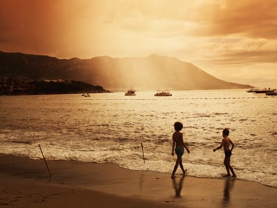 两个孩子走在海滩日落
